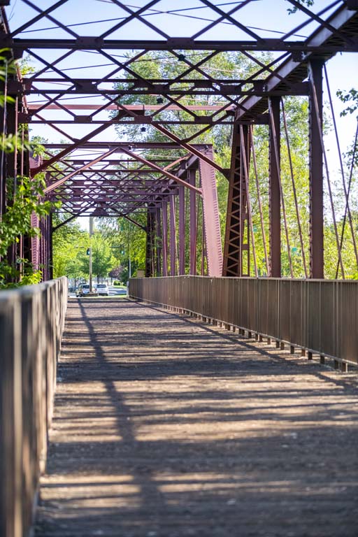 Pedestrian bridge with steel trusses and a shaded walkway in Caldwell, Idaho.